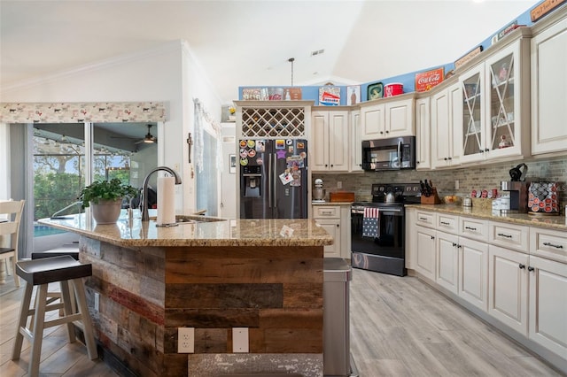 kitchen featuring vaulted ceiling, pendant lighting, sink, a kitchen island with sink, and stainless steel appliances