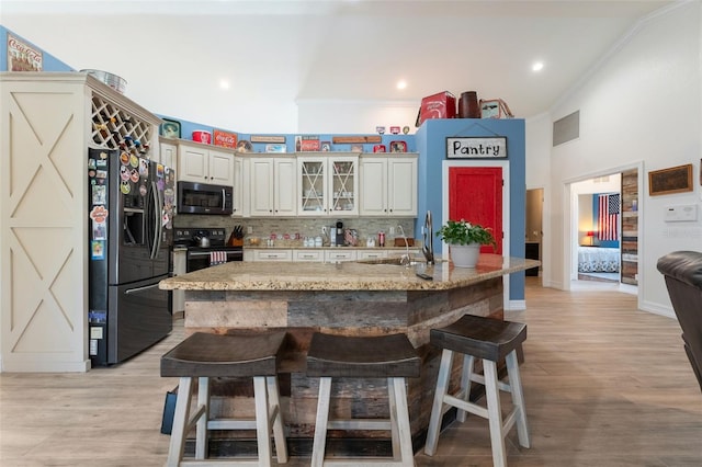 kitchen featuring light stone counters, appliances with stainless steel finishes, a kitchen island with sink, and a breakfast bar area