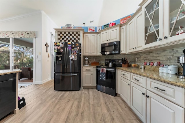 kitchen with vaulted ceiling, backsplash, light stone counters, and black appliances