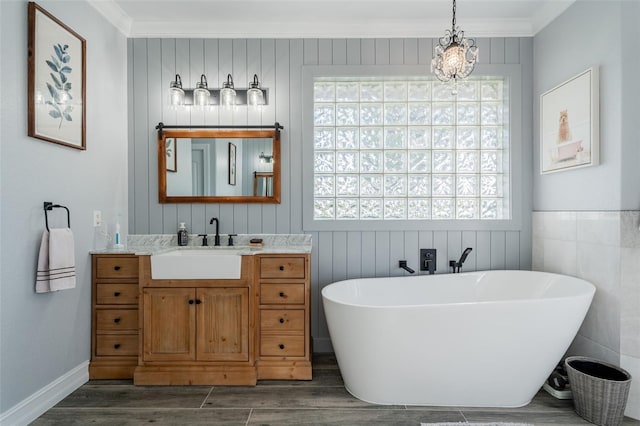 bathroom with ornamental molding, wood-type flooring, a bath, and vanity