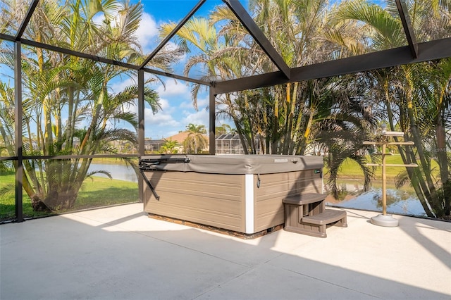 view of patio / terrace with a lanai, a hot tub, and a water view