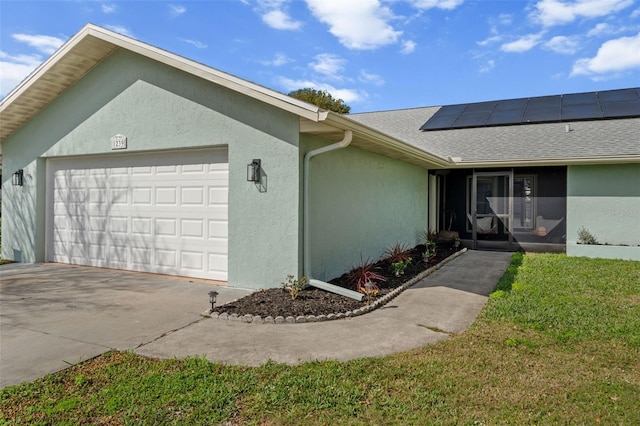 exterior space with roof with shingles, stucco siding, solar panels, an attached garage, and a front yard