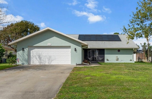 ranch-style home with a garage, concrete driveway, roof mounted solar panels, stucco siding, and a front yard