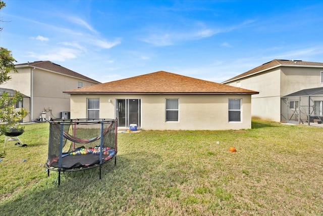 rear view of property featuring a yard and a trampoline