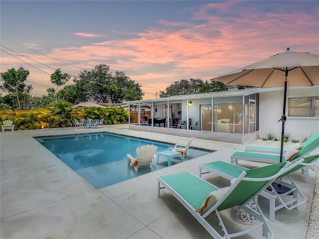 pool at dusk with a patio area