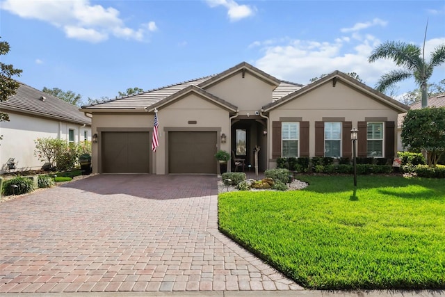 ranch-style home with a garage, decorative driveway, a front yard, and stucco siding