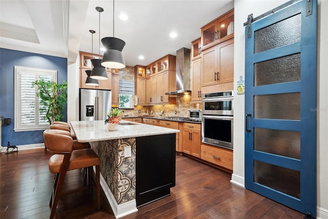 kitchen with decorative backsplash, appliances with stainless steel finishes, dark wood-type flooring, ornamental molding, and wall chimney range hood