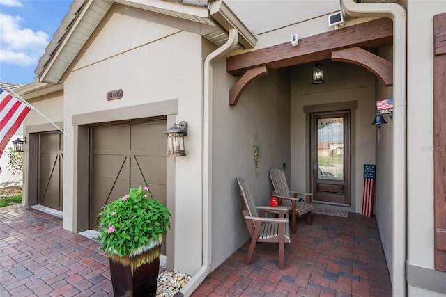 view of exterior entry featuring a garage, elevator, and stucco siding