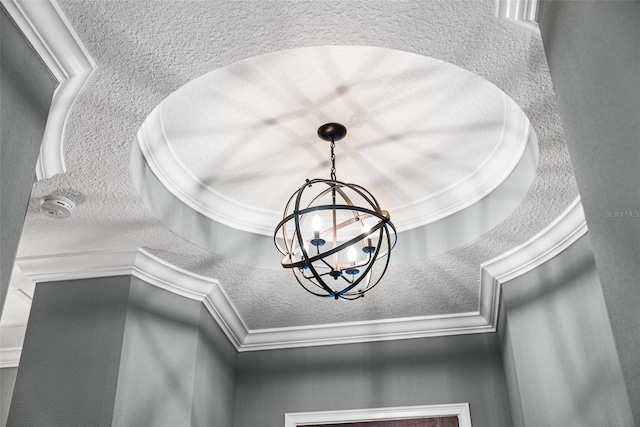 details featuring a textured ceiling, ornamental molding, and an inviting chandelier