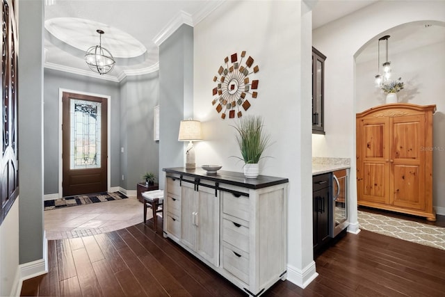 entryway featuring baseboards, ornamental molding, dark wood finished floors, and a notable chandelier