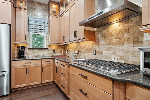 kitchen with stainless steel appliances, wall chimney range hood, dark wood-type flooring, and decorative backsplash