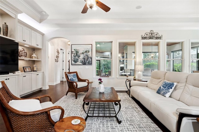 living area with baseboards, arched walkways, dark wood finished floors, ceiling fan, and crown molding