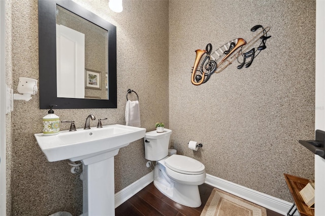 bathroom with baseboards, toilet, and wood finished floors