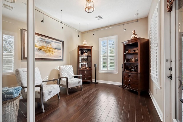 living area featuring baseboards, visible vents, and dark wood-type flooring