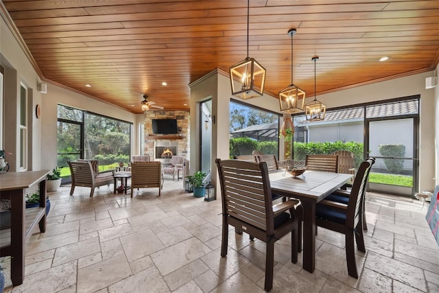 sunroom with wooden ceiling, an outdoor stone fireplace, and ceiling fan with notable chandelier