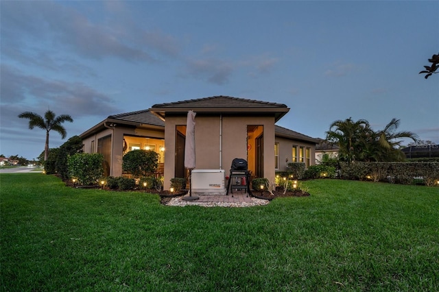 back of property featuring a yard and stucco siding