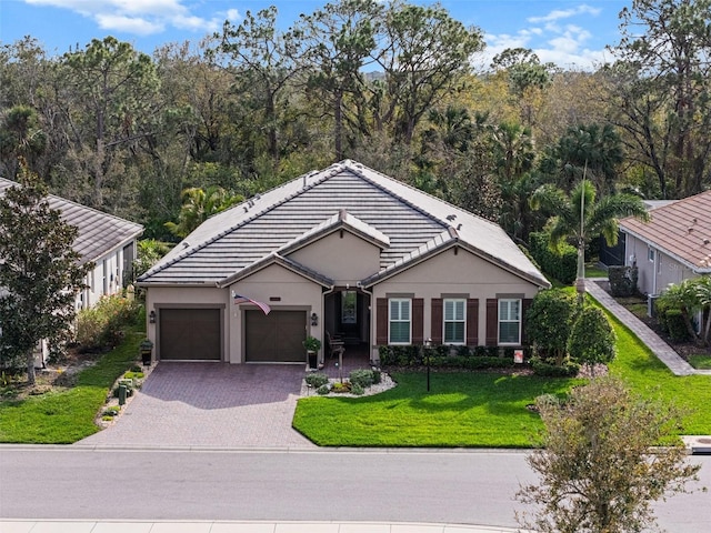 ranch-style home with a garage, a tiled roof, decorative driveway, stucco siding, and a front yard