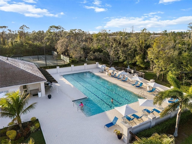 community pool with a patio area and fence