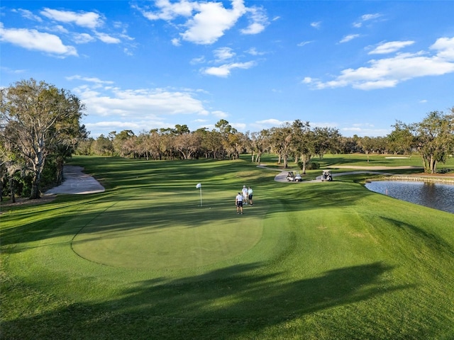 view of home's community featuring a water view, a yard, and golf course view