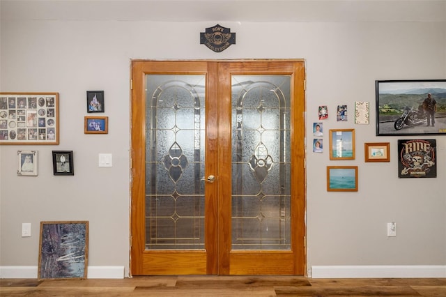 interior space featuring wood finished floors, french doors, and baseboards