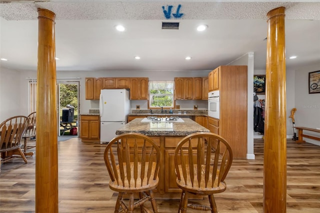 kitchen with white appliances, visible vents, light wood-style flooring, decorative columns, and recessed lighting