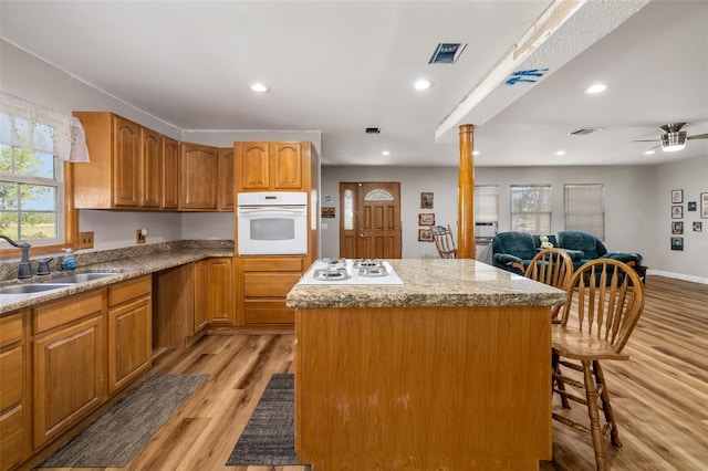 kitchen featuring visible vents, a kitchen island, white appliances, ornate columns, and a sink