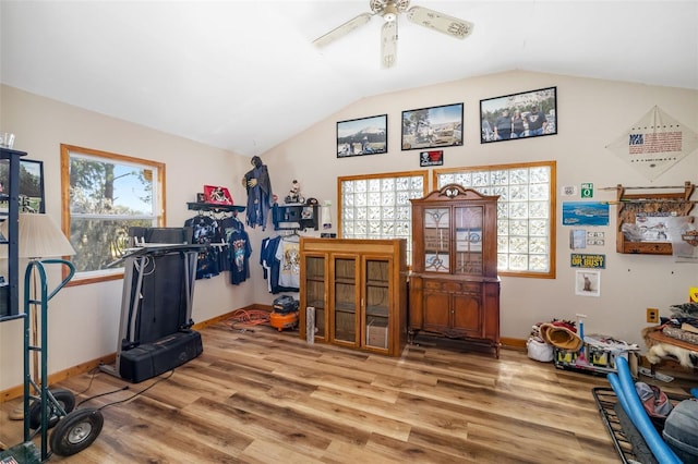 workout room with ceiling fan, baseboards, wood finished floors, and vaulted ceiling