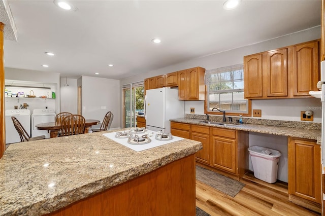 kitchen featuring white appliances, light wood finished floors, recessed lighting, separate washer and dryer, and a sink