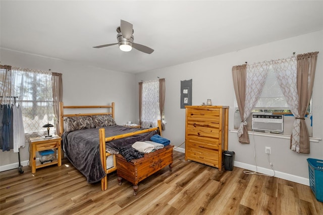 bedroom featuring ceiling fan, cooling unit, baseboards, and wood finished floors