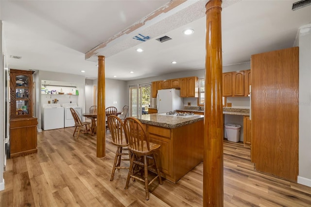 kitchen featuring visible vents, light wood-type flooring, independent washer and dryer, white appliances, and ornate columns