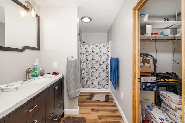 full bathroom with a shower stall, vanity, baseboards, and wood finished floors