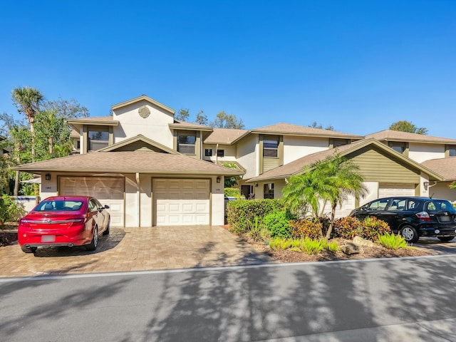 view of front of house with decorative driveway, an attached garage, and stucco siding