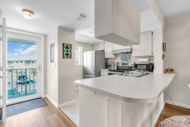 kitchen with stainless steel appliances, light countertops, white cabinetry, a sink, and a peninsula