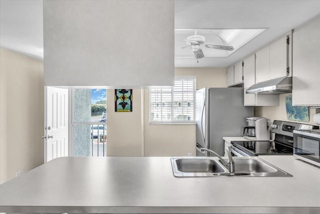 kitchen with white cabinets, appliances with stainless steel finishes, light countertops, under cabinet range hood, and a sink