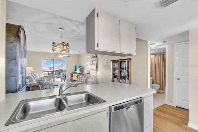 kitchen featuring open floor plan, light countertops, stainless steel dishwasher, and decorative light fixtures