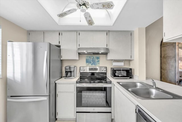 kitchen with a raised ceiling, appliances with stainless steel finishes, extractor fan, light countertops, and a sink