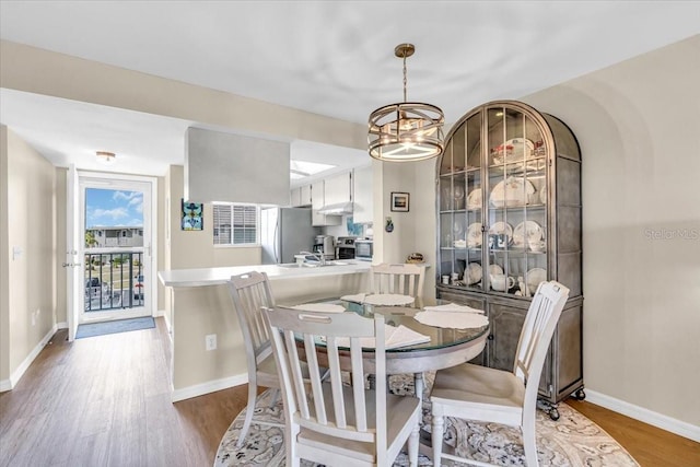 dining room featuring a chandelier, wood finished floors, and baseboards