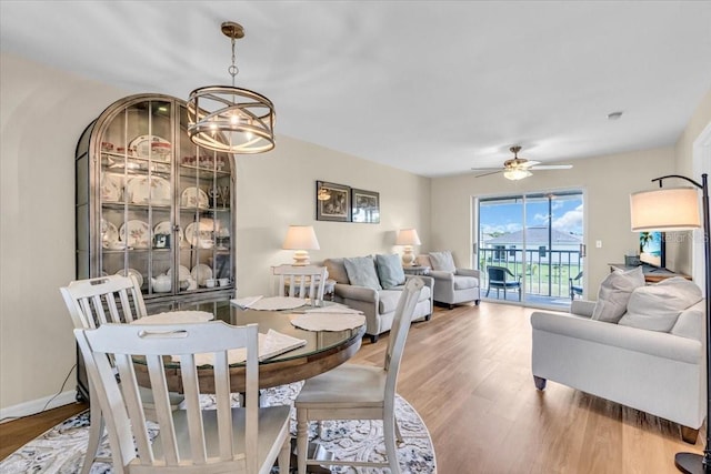 dining room with ceiling fan with notable chandelier, baseboards, and wood finished floors