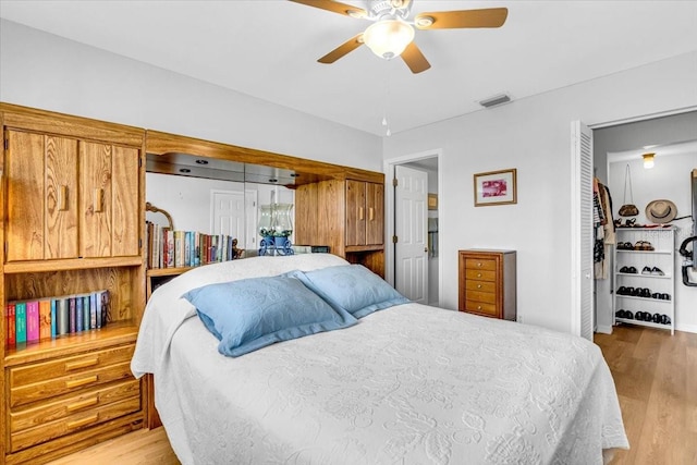 bedroom with a ceiling fan, visible vents, and wood finished floors