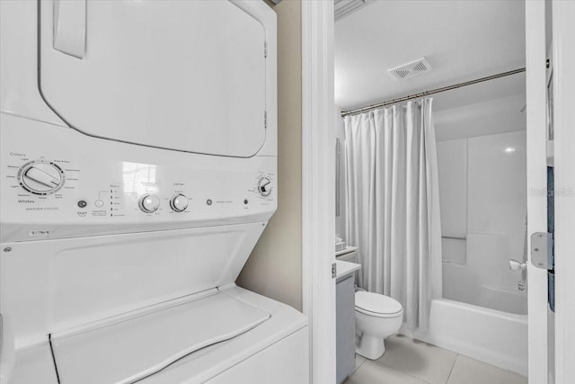 full bath with shower / tub combo with curtain, visible vents, toilet, stacked washer / dryer, and tile patterned flooring