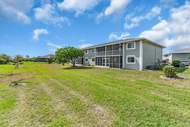 rear view of house featuring a lawn and a sunroom