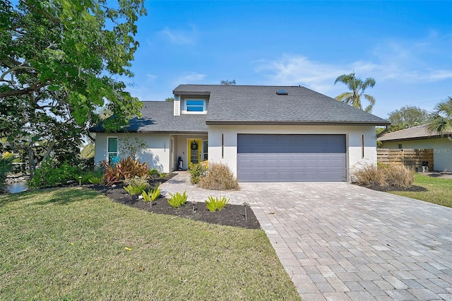 view of front of property with a shingled roof, an attached garage, decorative driveway, a front lawn, and stucco siding