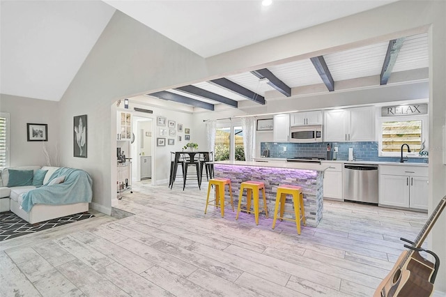 kitchen with appliances with stainless steel finishes, plenty of natural light, a sink, and light wood-style floors