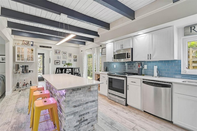 kitchen with light countertops, appliances with stainless steel finishes, a breakfast bar, and decorative backsplash