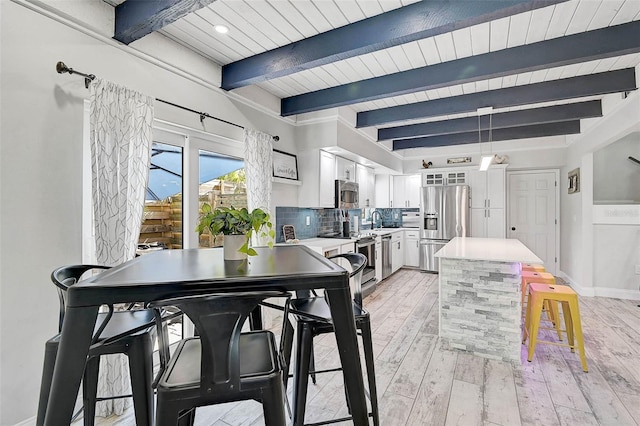 dining area with wooden ceiling, beamed ceiling, light wood-style flooring, and baseboards