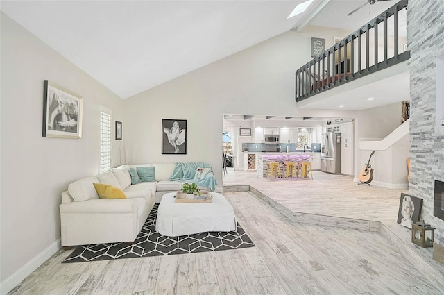 living room featuring light wood finished floors, a skylight, a wealth of natural light, and baseboards