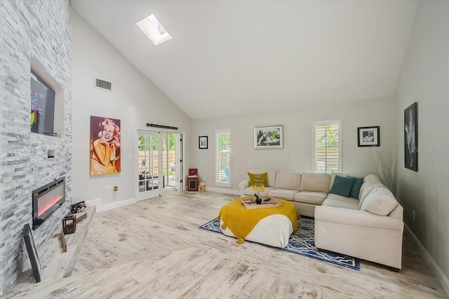 living area with high vaulted ceiling, a skylight, visible vents, and wood finished floors