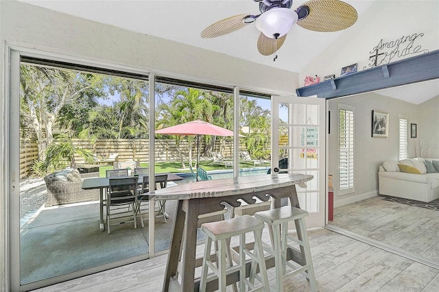 sunroom with lofted ceiling and a ceiling fan