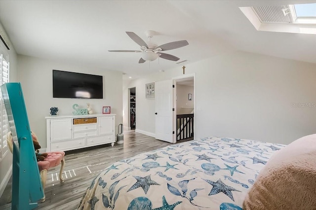 bedroom with visible vents, lofted ceiling with skylight, wood finished floors, and a ceiling fan