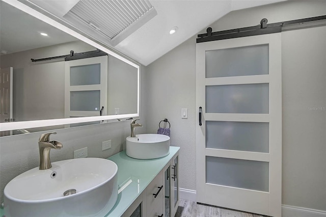 bathroom with lofted ceiling, double vanity, a sink, and wood finished floors